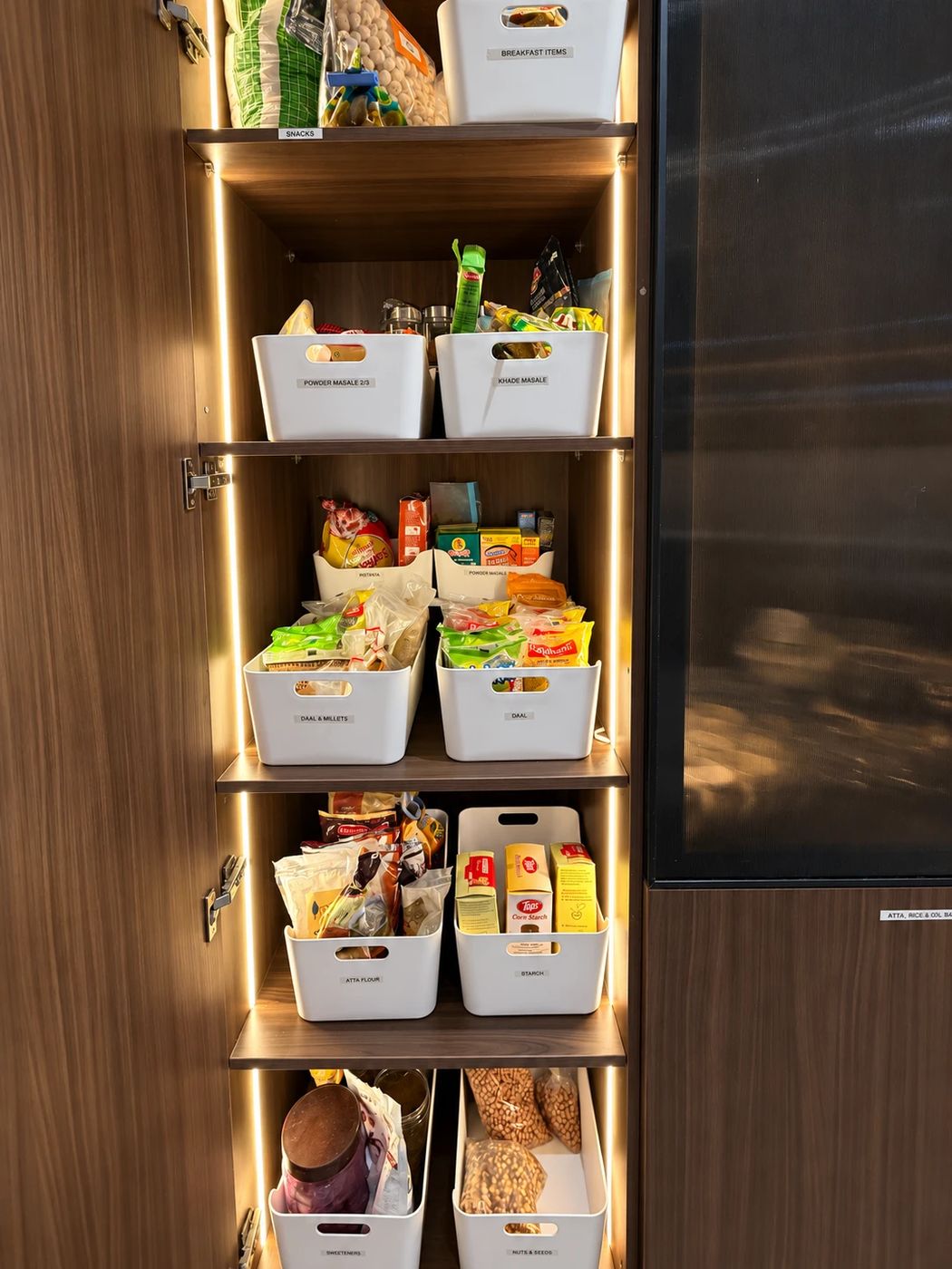 Pantry shelves with labelled white bins for staples and snacks