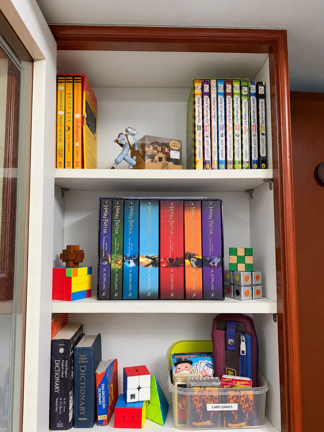 Kids' bookshelf with book series, puzzles and a labelled card games box